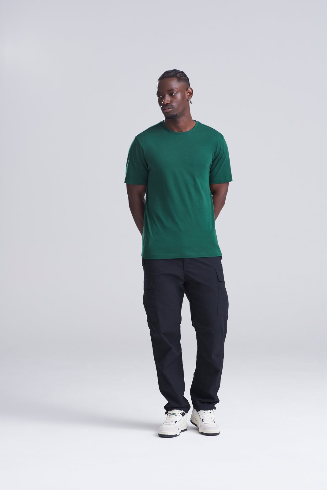 Model wearing a bottle green AWDis 150 T-shirt with dark trousers