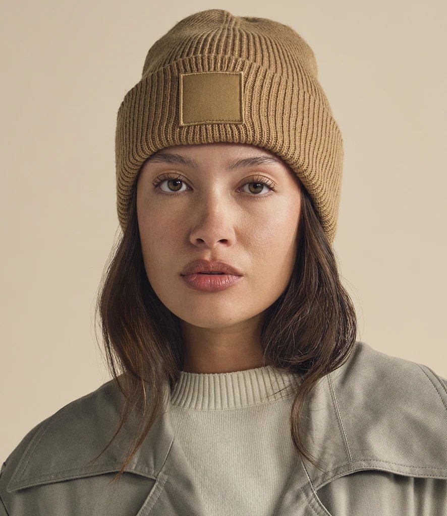 Model wearing a biscuit Beechfield Deep Cuff Tonal Patch Beanie, front view