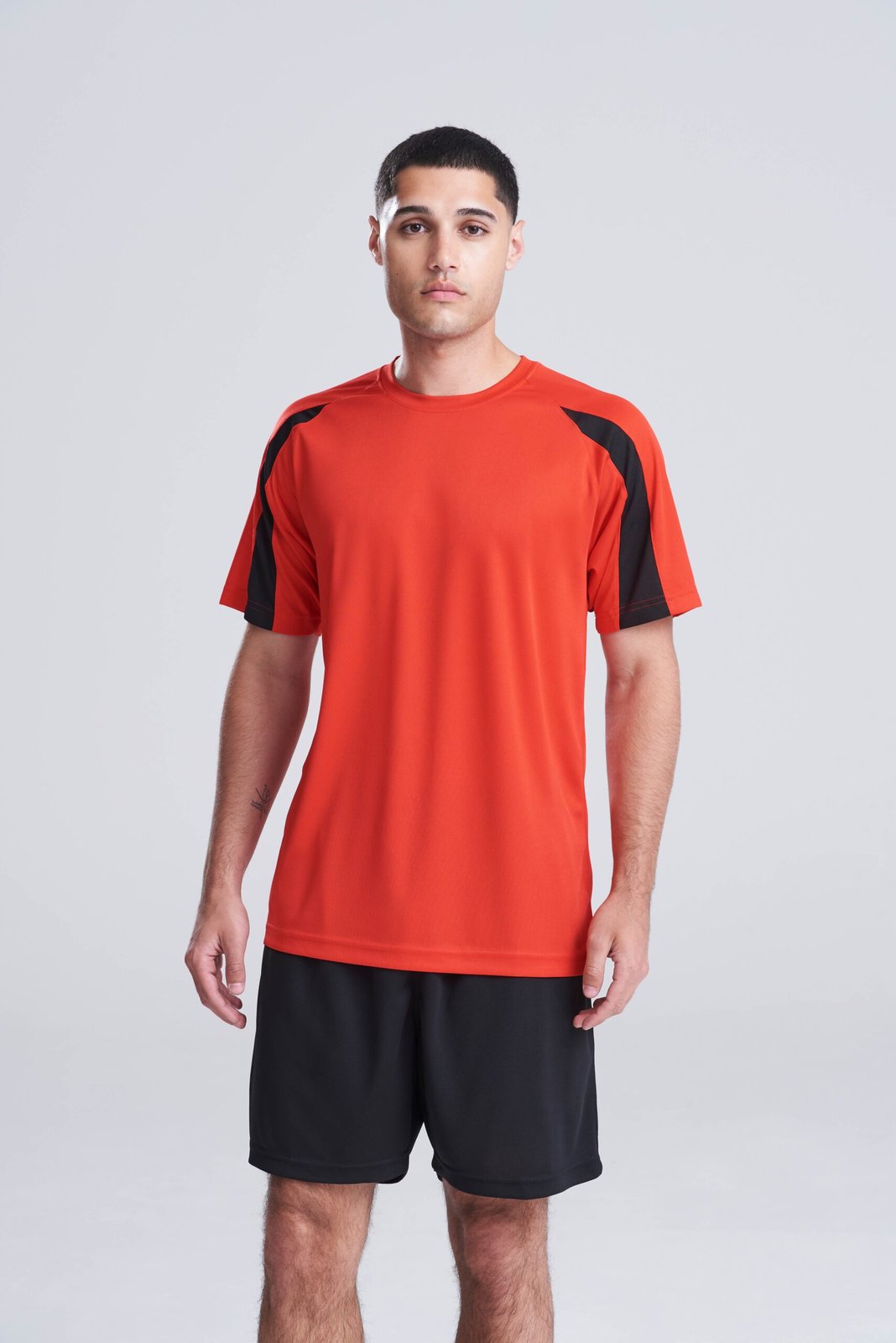 Model wearing a red AWDis Cool Contrast T-shirt with black side panels, front view