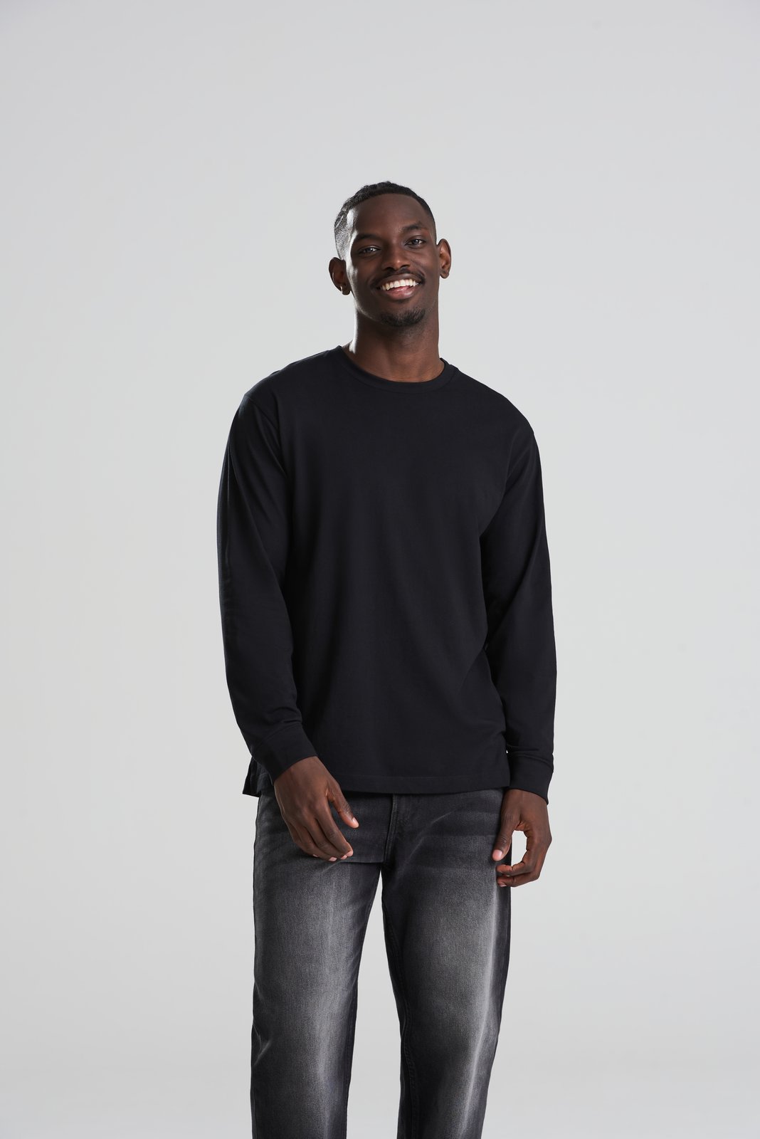Model wearing a black AWDis 180 long sleeve T-shirt with grey jeans